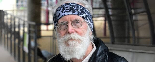 A photo a man with grey hair and beard wearing glasses